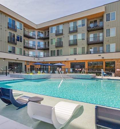 an apartment building with a swimming pool and chairs