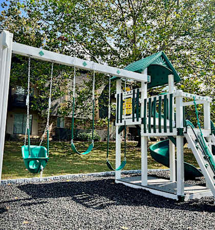 a playground with a swing set and a play house