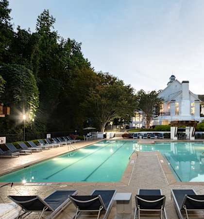 a swimming pool with chairs and a house in the background