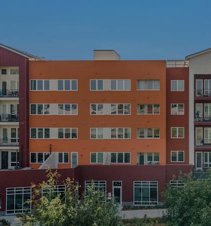 an exterior view of an apartment building with trees in the foreground