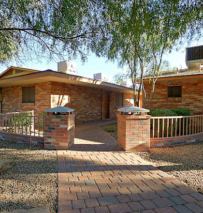 a brick house with a pathway and a tree