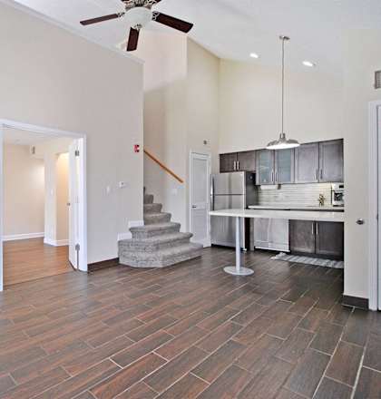the living room and kitchen of a new home with a ceiling fan