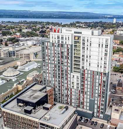 A tall building with a red and white logo on the top stands out in a cityscape.