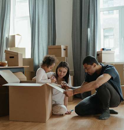 a man and woman sitting on the floor with boxes and a child looking at a