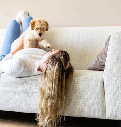a girl laying on a couch with her dog on top of it