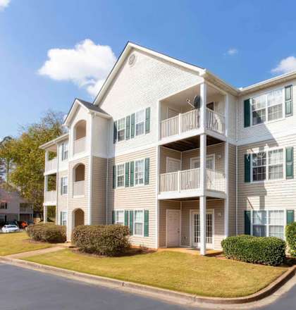A large apartment building with a white facade and green shutters.