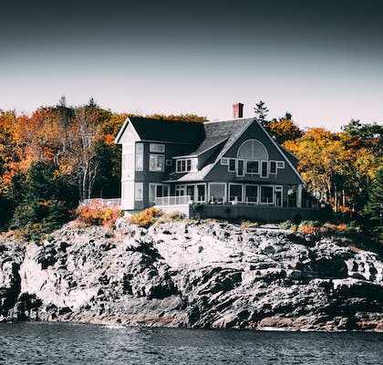 a house on a rocky island next to a body of water