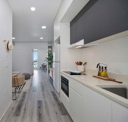 a kitchen with white cabinets and a long hallway to a living room