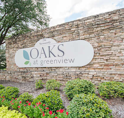 a sign that says oaks at greenview in front of a brick wall