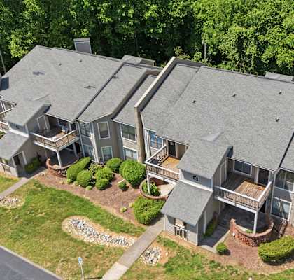 A large house with a grey roof and a driveway in front.