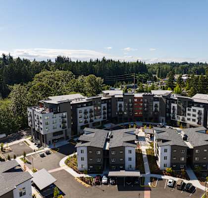 an aerial view of a group of apartment buildings with trees in the background