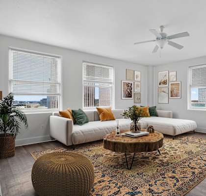 A living room with a white couch, a brown ottoman, and a rug.
