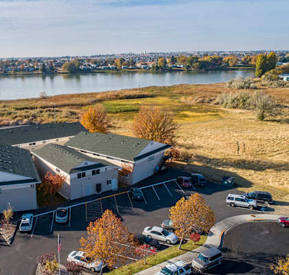 Aerial view of the community with grass fields leading to Moses Lake behind The Lakes Apartments.at The Lakes Apartments, Moses Lake