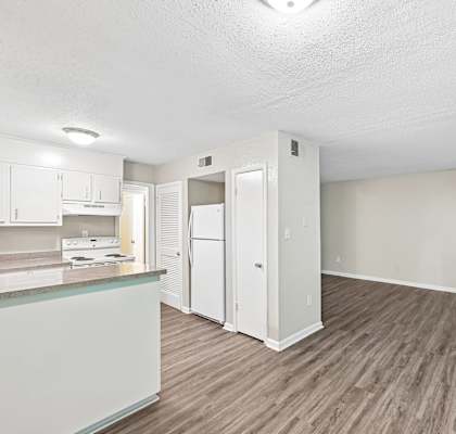A kitchen with white cabinets and a wooden floor.