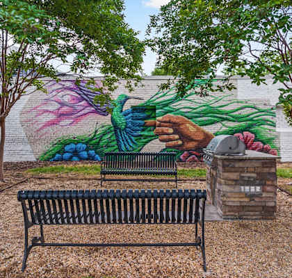 A mural of a hand holding a plant is painted on a wall behind a bench.