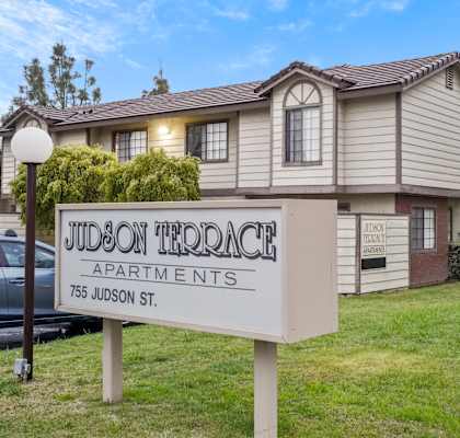A sign for Judson Terrace Apartments stands in front of a building.