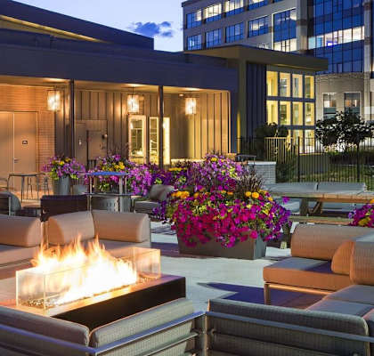 a patio with couches and a fire pit in front of a building
