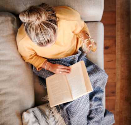 a woman sitting on a couch reading a book at Residences at the Street, Washington, PA, 15301