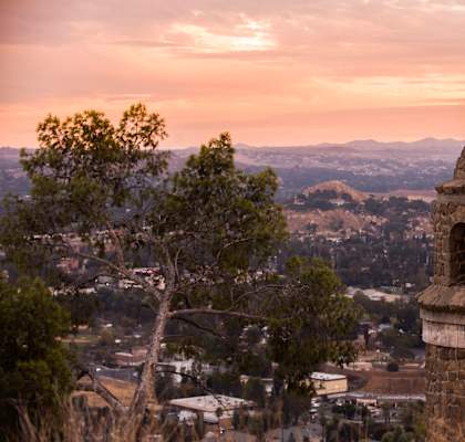 the top of a stone tower with a cross on top of it overlooking a city