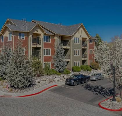 A large apartment complex with a parking lot in front.