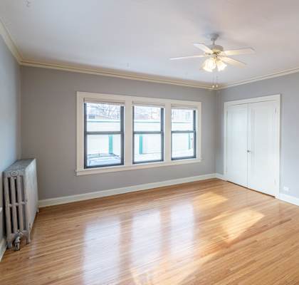 A room with a ceiling fan and wooden floors.