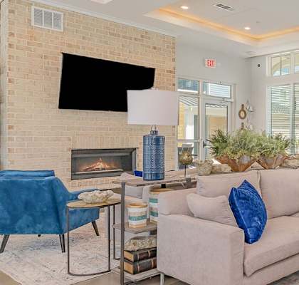A living room with a fireplace and a flat screen TV mounted on the wall. at The Banks at Bridgewater Apartments, Little River, SC, 29566