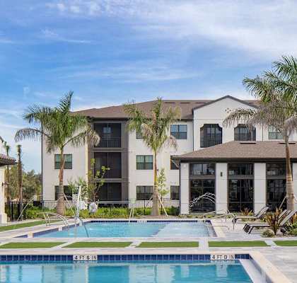 A swimming pool is surrounded by palm trees and a row of houses at Las Palmas Apartments, Fort Myers, 33913