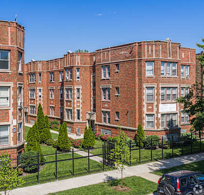 A red brick building with a black fence in front.
