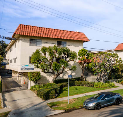 a row of houses with red roofs and cars parked in front of them
