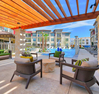 an outdoor shaded patio with lounge furniture and a pool at Park at Rialto Apartments, San Antonio, TX 78257arge Balcony at Park at Rialto Apartments, San Antonio