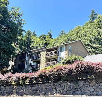 a view of a house with a stone wall and trees