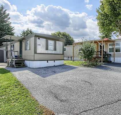an rv is parked on a gravel driveway in front of a house
