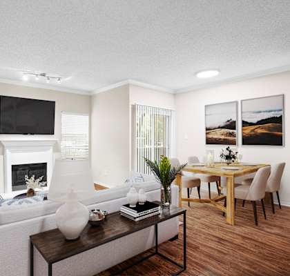 a living room with a fireplace and a dining room in the background at Creekview Apartment Homes, Texas