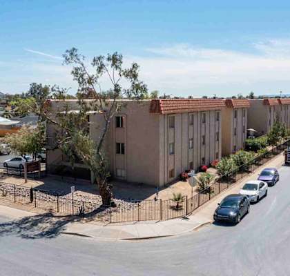 A street view of a residential area with apartment buildings and parked cars.