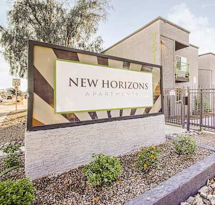 A sign for New Horizons Apartments is displayed in front of a building.