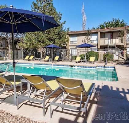 A pool with yellow chairs and blue umbrellas.