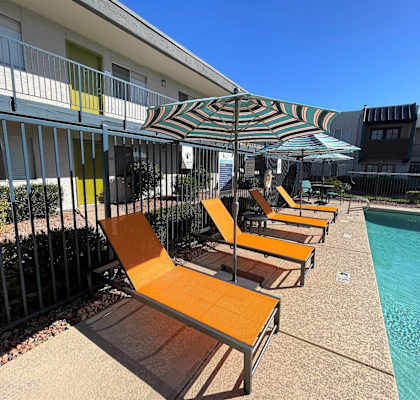 A row of sun loungers are on the edge of a pool.