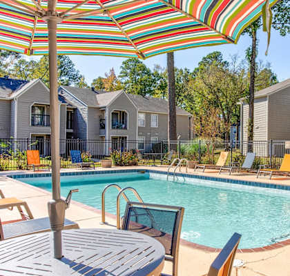 A pool area with a table and chairs and umbrellas.