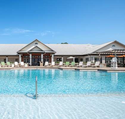 a large pool with lounge chairs and umbrellas in front of a building at Century Belmont Station, Louisville