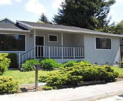 A house with a grey roof and a white wall with a small porch.