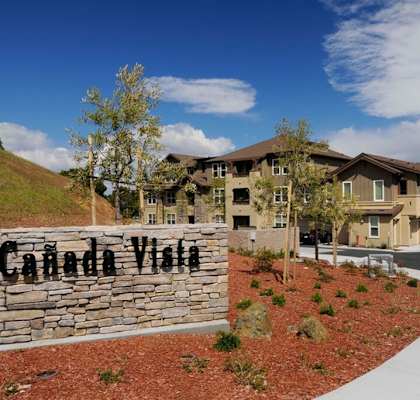 A stone wall with Canada Vista written on it in front of a building.