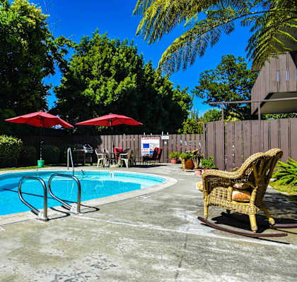 a pool in a backyard with a chair and umbrellas