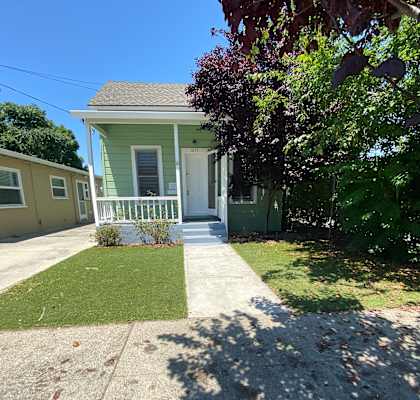 1055 Market st Santa Clara CA  a green house with a white porch and a tree in front of it