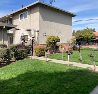 A house with a fence and a green lawn in front.