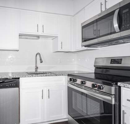 A kitchen with white cabinets and black appliances.