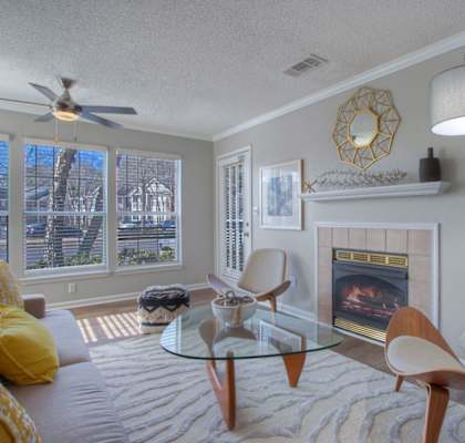 Living room 2 bedroom model with very large windows, wood like plank flooring, new ceiling fan and lighting package, white trim, fireplace and modern decor.