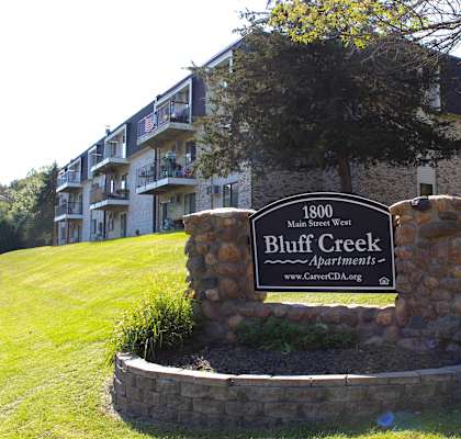 A sign for Bluff Creek Apartments sits in front of a building.