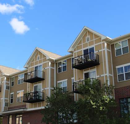Apartment building with balconies and trees in front.