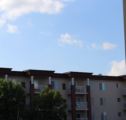 Apartment building with balconies and trees in front.