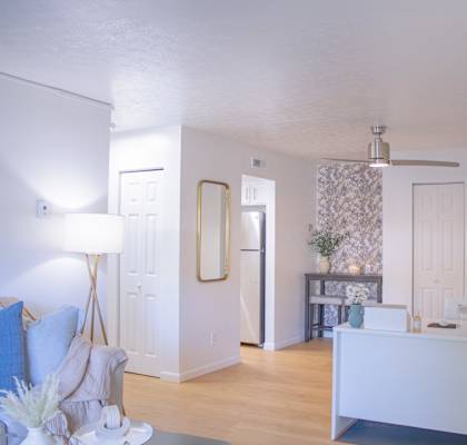 a living room and dining room with a white couch and a table and a kitchen